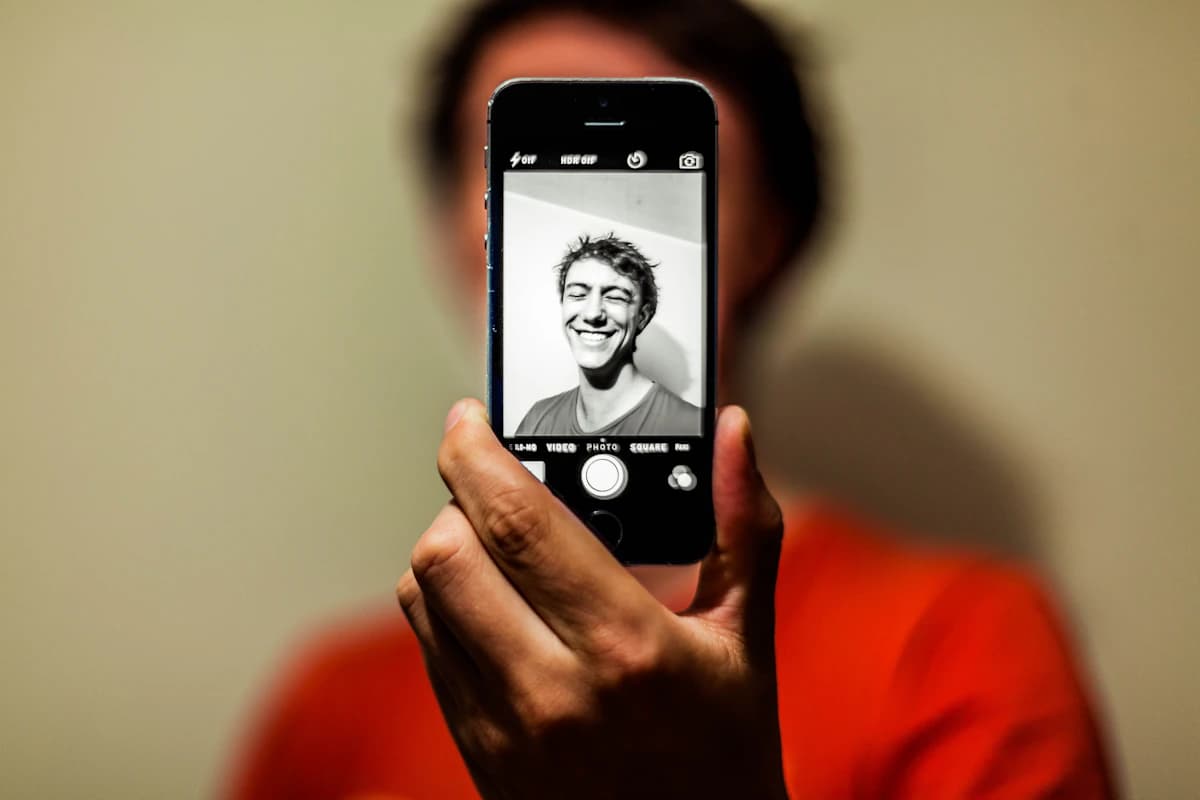 Person holding a phone taking a front-facing portrait, the typical starting point for a face-rating app
